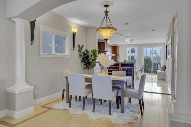 dining space with light wood-type flooring and ornate columns