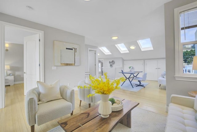 living room featuring vaulted ceiling with skylight and light hardwood / wood-style flooring