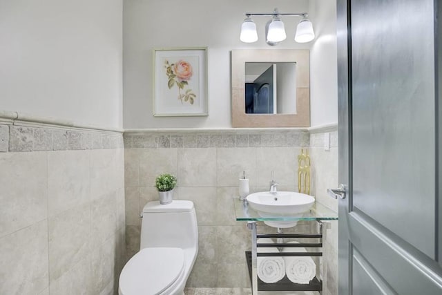 bathroom featuring sink, tile walls, and toilet