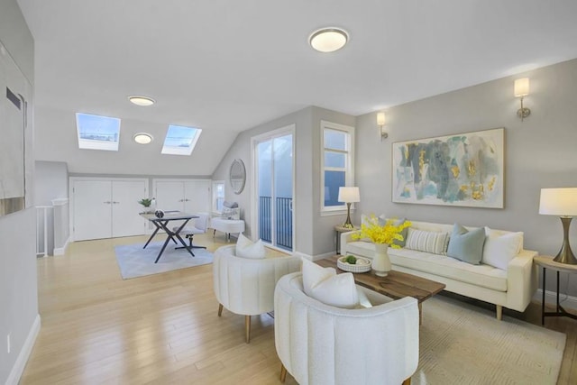 living room with vaulted ceiling with skylight and light hardwood / wood-style flooring