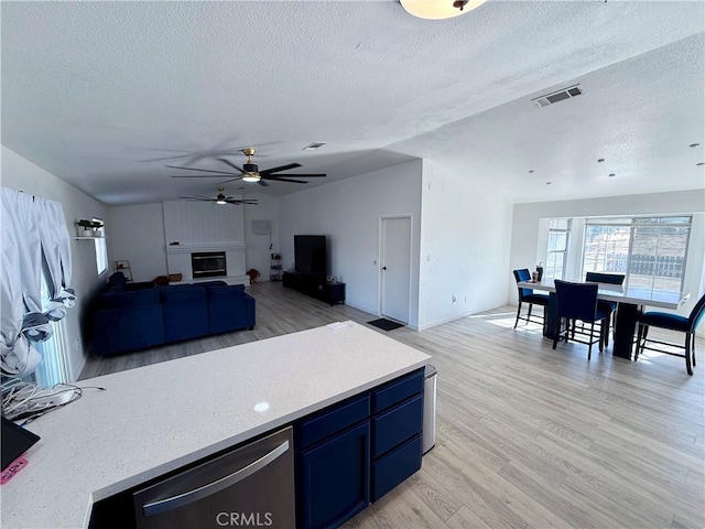 kitchen featuring a textured ceiling, light wood-type flooring, ceiling fan, and lofted ceiling