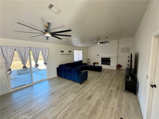 living room with ceiling fan, light wood-type flooring, and a fireplace