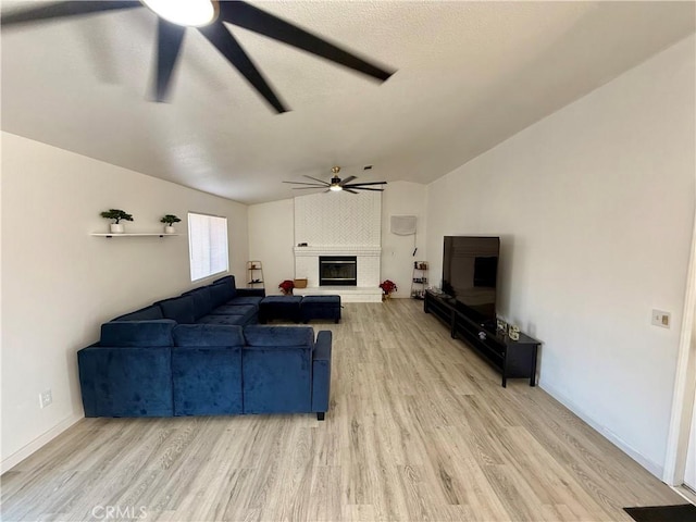 living room with a textured ceiling, wood-type flooring, a fireplace, and vaulted ceiling