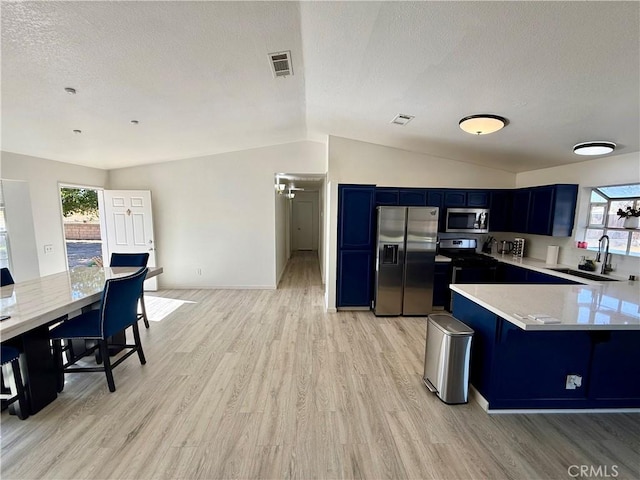 kitchen with blue cabinetry, sink, light hardwood / wood-style flooring, lofted ceiling, and appliances with stainless steel finishes