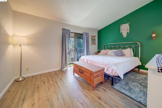 bedroom featuring access to exterior, light hardwood / wood-style floors, and lofted ceiling