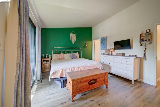 bedroom featuring light wood-type flooring and vaulted ceiling