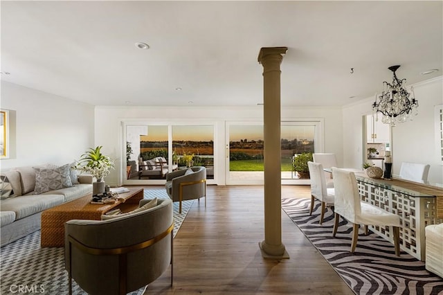 living room with a chandelier, dark hardwood / wood-style floors, ornate columns, and ornamental molding