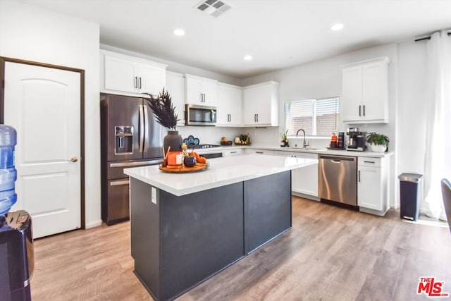 kitchen featuring white cabinetry, sink, light hardwood / wood-style flooring, a kitchen island, and appliances with stainless steel finishes