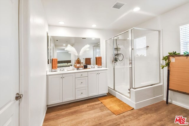 bathroom featuring hardwood / wood-style floors, vanity, and a shower with shower door