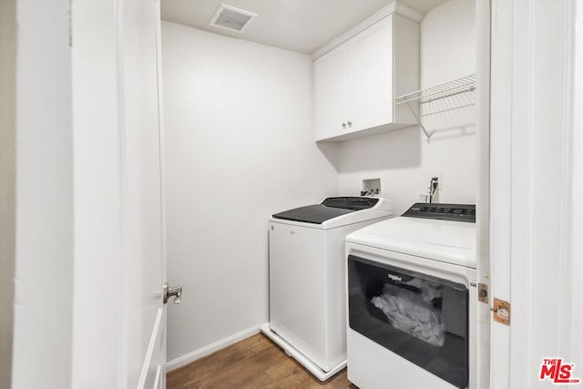 laundry room featuring hardwood / wood-style floors, cabinets, and independent washer and dryer