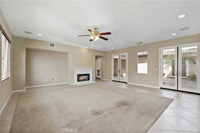 unfurnished living room with light tile patterned floors, visible vents, a glass covered fireplace, and recessed lighting