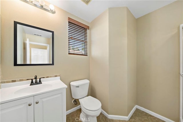 bathroom with toilet, visible vents, vanity, and baseboards