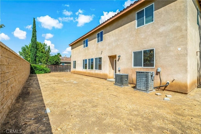 back of property with central AC, a fenced backyard, and stucco siding