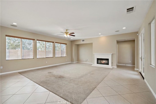 unfurnished living room with light tile patterned floors, recessed lighting, visible vents, light carpet, and a lit fireplace