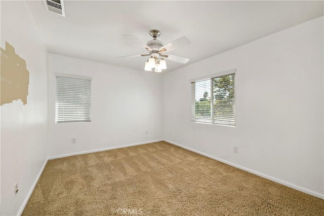 carpeted spare room featuring visible vents, ceiling fan, and baseboards