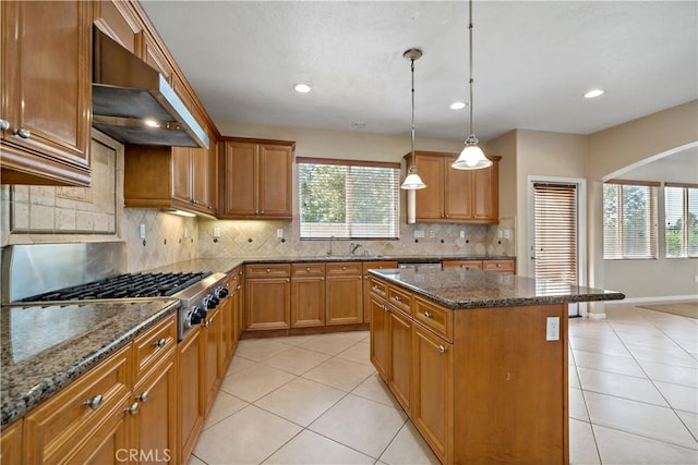 kitchen featuring brown cabinetry, a kitchen island, and ventilation hood