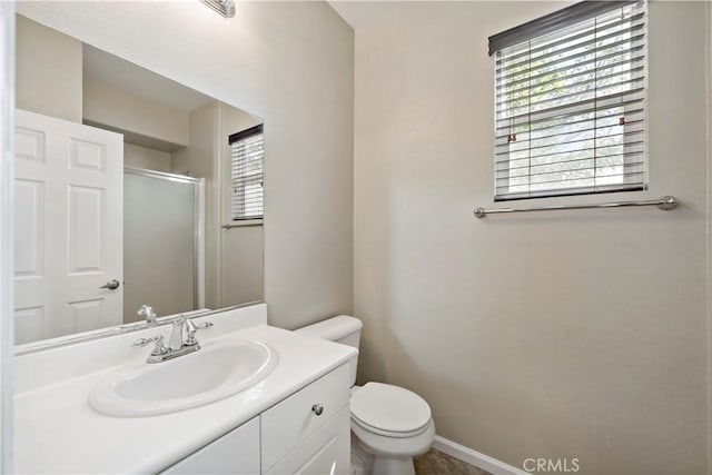 bathroom featuring a stall shower, baseboards, vanity, and toilet