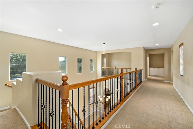 hallway featuring baseboards, recessed lighting, an upstairs landing, and light colored carpet