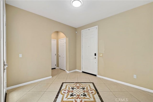 entryway featuring baseboards, arched walkways, and light tile patterned flooring