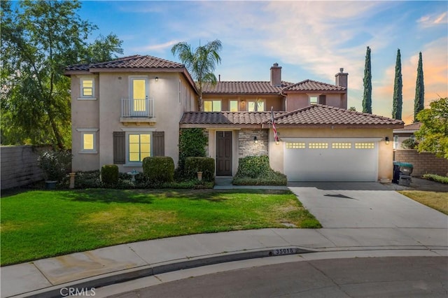 mediterranean / spanish home featuring an attached garage, a yard, concrete driveway, and stucco siding