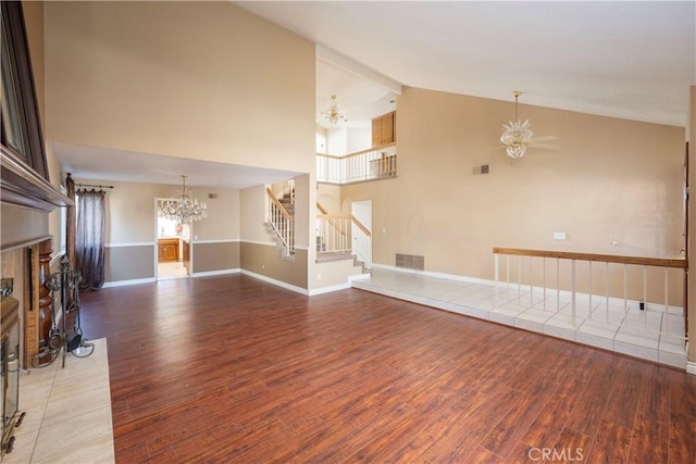 unfurnished living room with high vaulted ceiling, a fireplace, ceiling fan with notable chandelier, and hardwood / wood-style floors