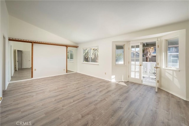 unfurnished room featuring lofted ceiling and light hardwood / wood-style floors