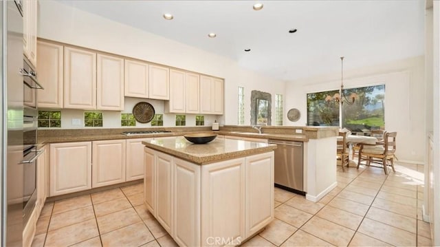 kitchen with hanging light fixtures, an inviting chandelier, kitchen peninsula, a kitchen island, and appliances with stainless steel finishes