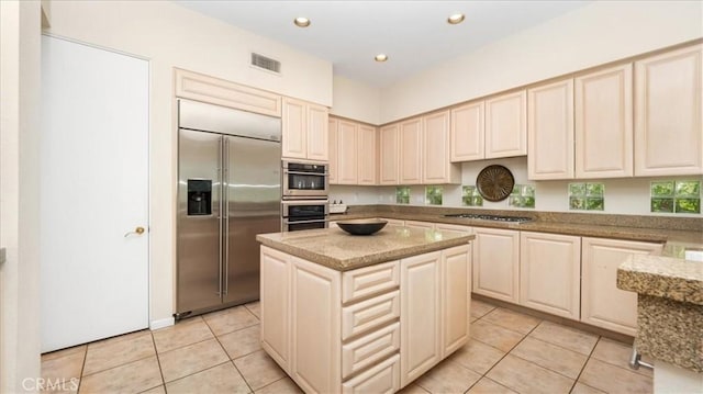 kitchen featuring light stone counters, light tile patterned flooring, stainless steel appliances, and a kitchen island