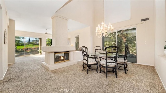 carpeted dining space with ceiling fan with notable chandelier and a multi sided fireplace