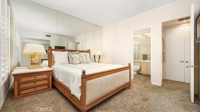 bedroom featuring light carpet and connected bathroom