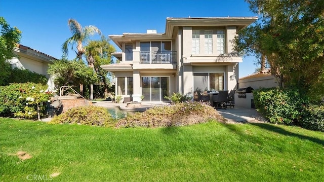 rear view of house featuring a lawn, a patio area, and a balcony