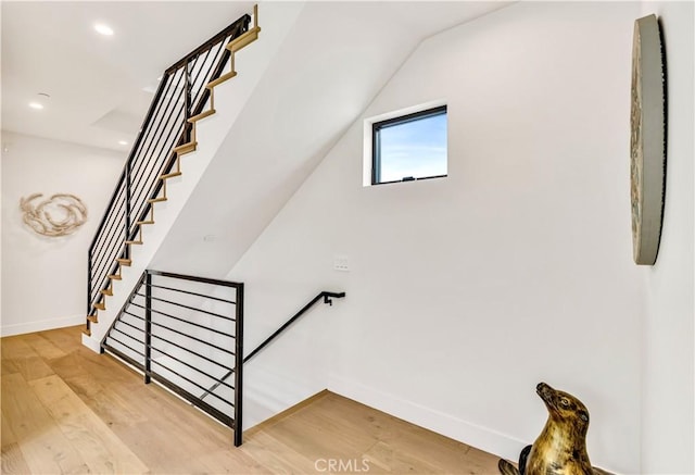 stairway featuring lofted ceiling and wood-type flooring