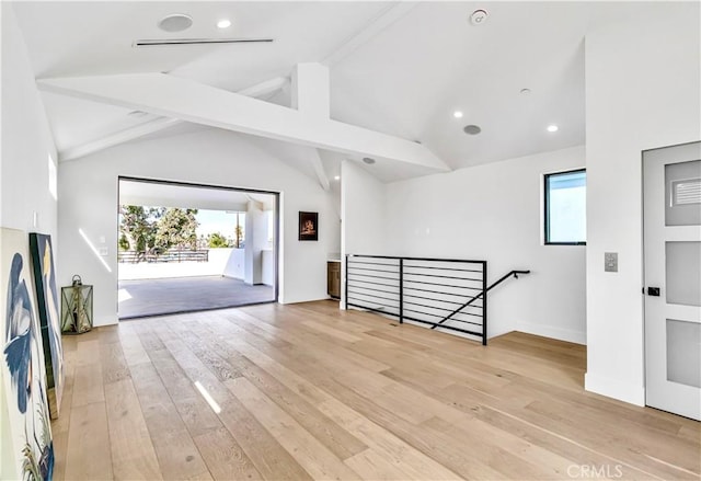 interior space featuring lofted ceiling with beams, a wealth of natural light, and light hardwood / wood-style flooring