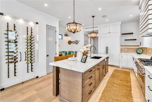 kitchen featuring sink, white cabinetry, a kitchen island with sink, and an inviting chandelier