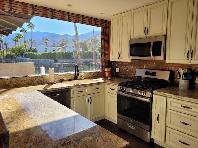 kitchen with a mountain view, cream cabinetry, stainless steel appliances, and sink