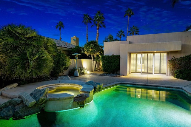 pool at night with an in ground hot tub