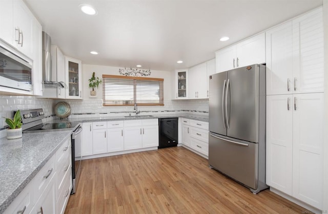 kitchen with tasteful backsplash, light hardwood / wood-style floors, light stone counters, white cabinetry, and stainless steel appliances