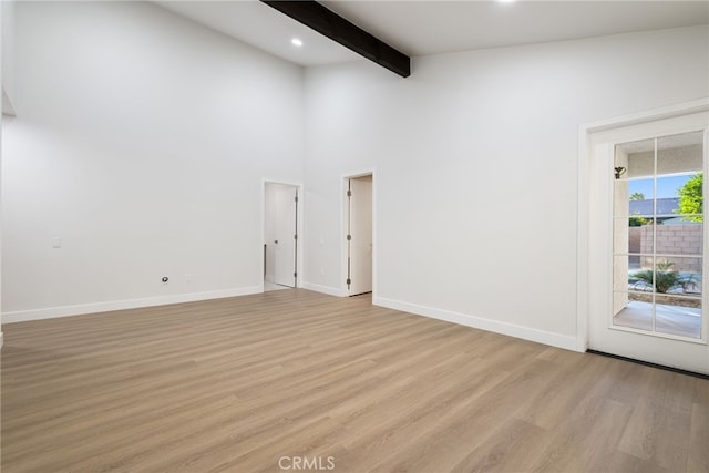 empty room featuring beam ceiling, high vaulted ceiling, and light hardwood / wood-style flooring