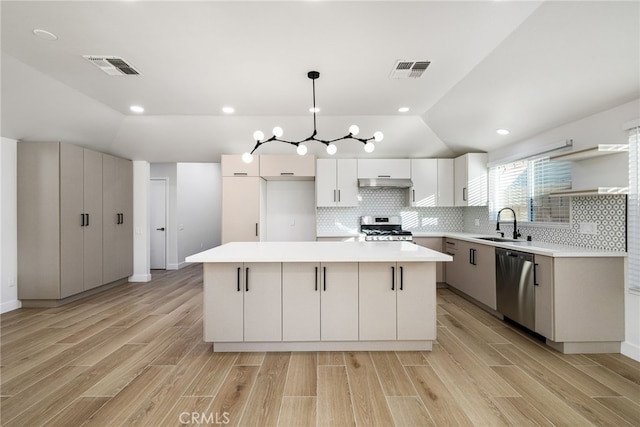 kitchen featuring white cabinets, decorative light fixtures, a kitchen island, and appliances with stainless steel finishes