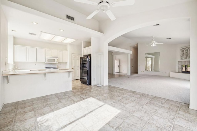 kitchen with white cabinetry, kitchen peninsula, white appliances, light carpet, and a breakfast bar