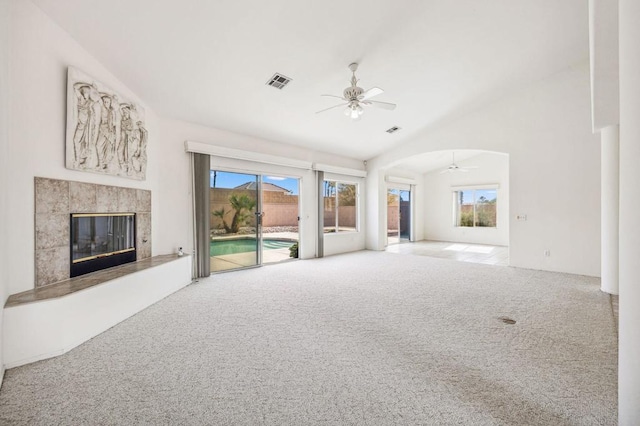 unfurnished living room with a tile fireplace, light colored carpet, ceiling fan, and lofted ceiling