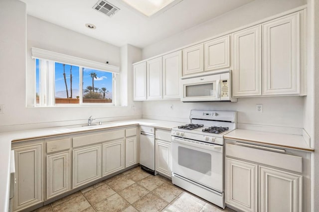 kitchen featuring sink, light tile patterned flooring, and white appliances