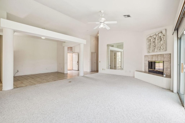 unfurnished living room with ceiling fan, vaulted ceiling, carpet floors, and a tiled fireplace