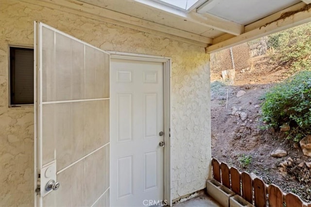 doorway to property with fence and stucco siding