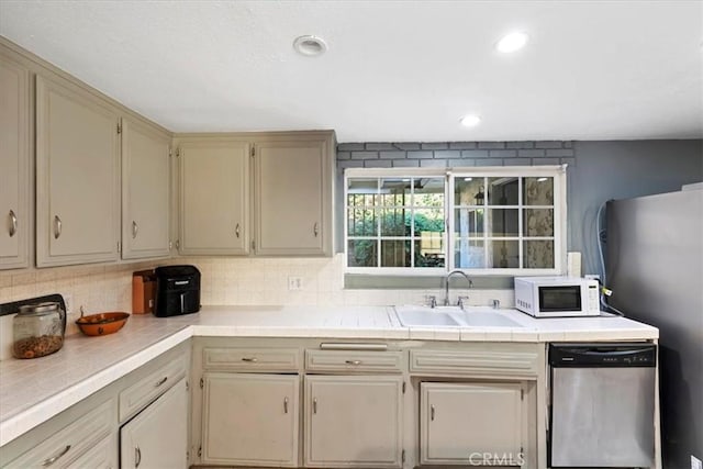 kitchen featuring light countertops, a sink, stainless steel dishwasher, and white microwave