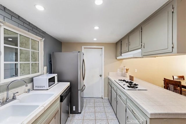 kitchen featuring under cabinet range hood, appliances with stainless steel finishes, a sink, and recessed lighting