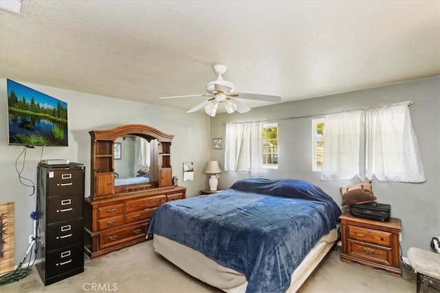 bedroom featuring a ceiling fan, light colored carpet, and a textured ceiling