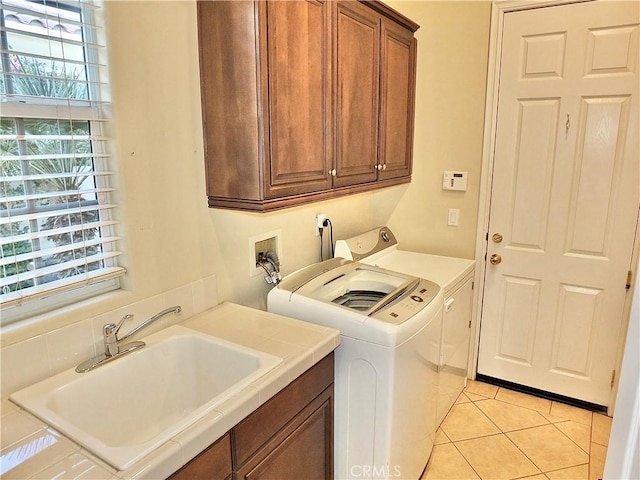 laundry room featuring light tile patterned floors, cabinets, washer and clothes dryer, and sink