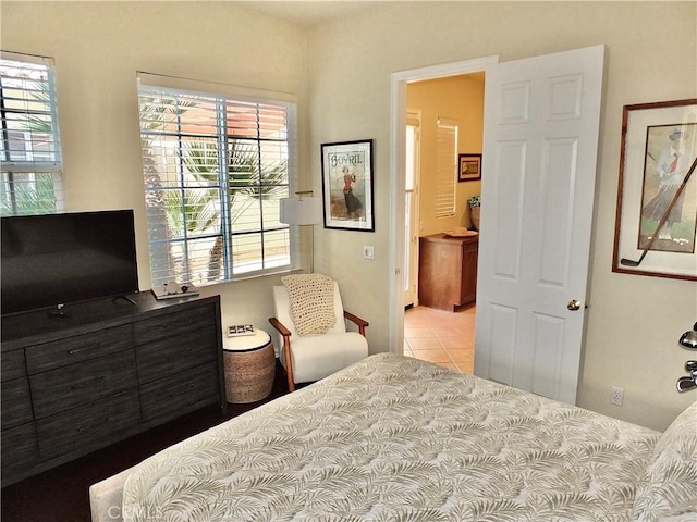 bedroom with ensuite bathroom and light tile patterned flooring