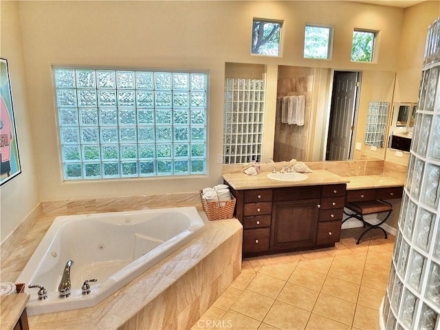 bathroom with tiled bath, vanity, and tile patterned flooring